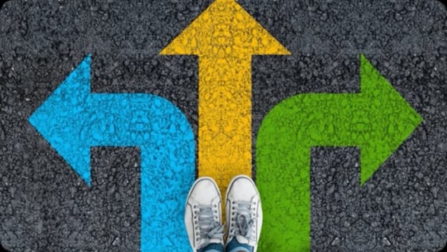 Feet standing at a crossroads with blue, yellow, and green arrows pointing different directions.