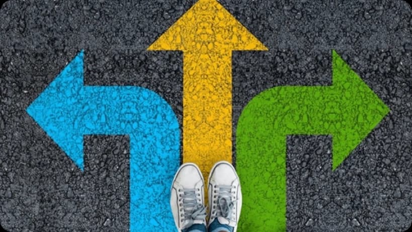 Feet standing at a crossroads with blue, yellow, and green arrows pointing different directions.