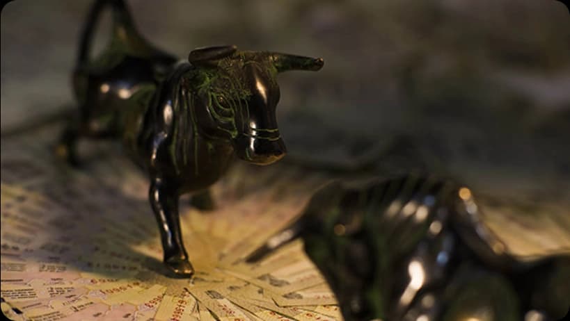 Two dark bull statues face each other on financial papers, symbolizing market dynamics.