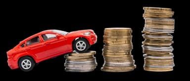 A red toy car drives over increasing stacks of coins on a black background.